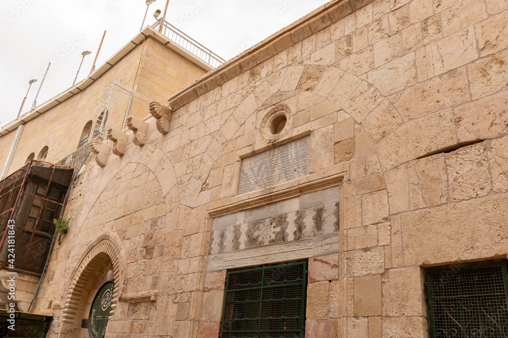 The facade of a residential building decorated with decorative stucco in the Arabian style and suras from the Koran, carved in stone, in the old city of Jerusalem, Israel