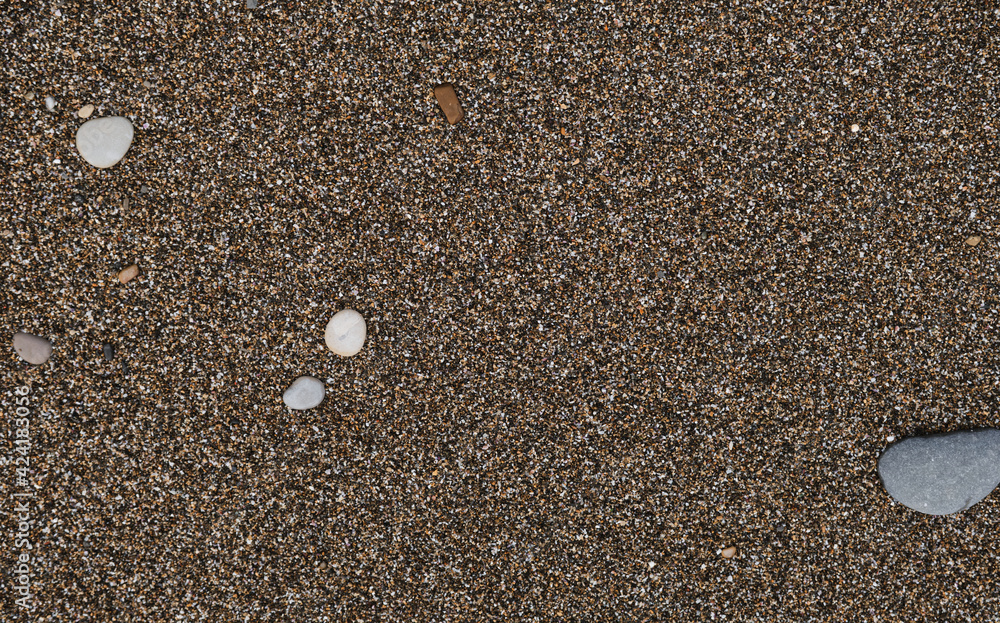 The Black Sea coast and its shore. Minimalistic sand background and space for text or ad design. Sand and small round stones close up. The Black Sea coast and its shore. Minimalistic sand background and space for text or ad design. Sand and small round stones close up.