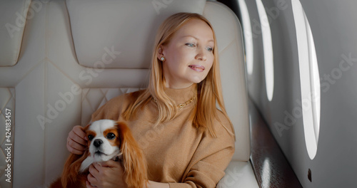 Elegant mature woman sitting inside private jet with adorable dog