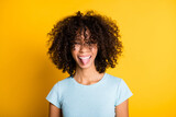 Photo of sweet childish dark skin wavy lady wear blue t-shirt showing tongue out isolated yellow color background