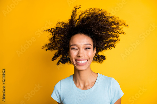 Photo of funny funky dark skin curly girl dressed blue t-shirt air blowing face isolated yellow color background