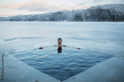 Man swimming in frozen lake