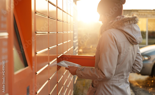 Fotografie Woman picks up mail from automated self-service post terminal machine