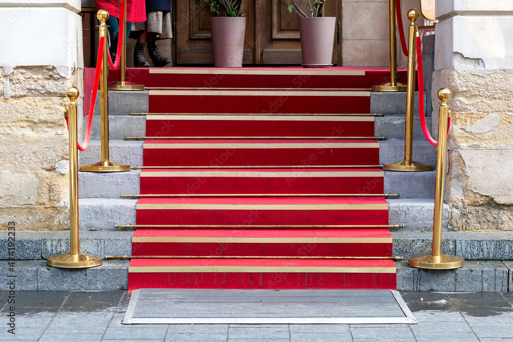 Red carpet on the stairs to the solemn event for guests, on both sides of the track gilded decorative columns.