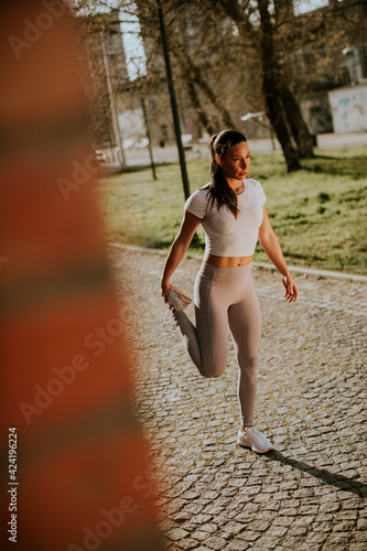 Young woman stretching during training in the urban environment