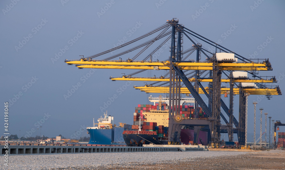 Logistics and container loading by large barges by sea in a harbor full of containers waiting to be transported