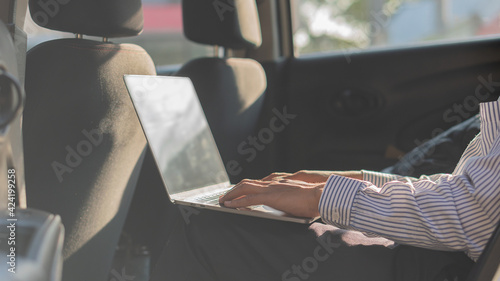 Business man working in a car on a laptop