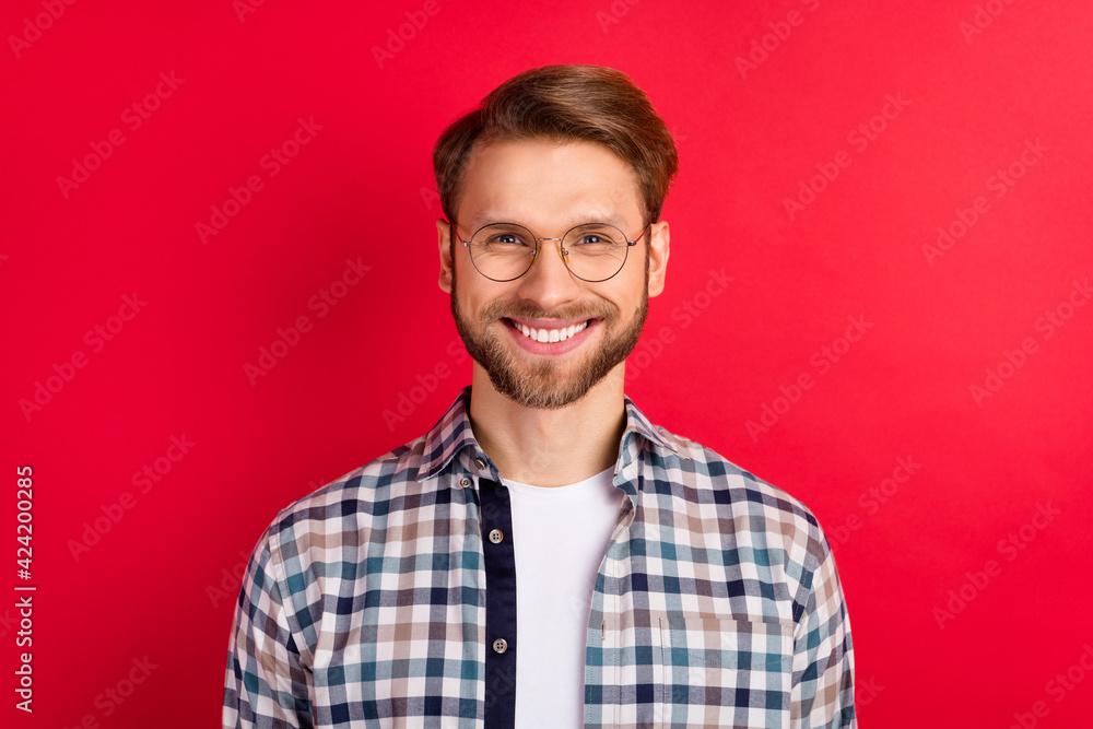 Photo of pretty charming young guy wear checkered shirt glasses smiling isolated red color background Photo of pretty charming young guy wear checkered shirt glasses smiling isolated red color background
