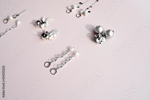 Set of earrings with pearls and chains on pastel violet background. Trendy stylish jewelry. Female blog