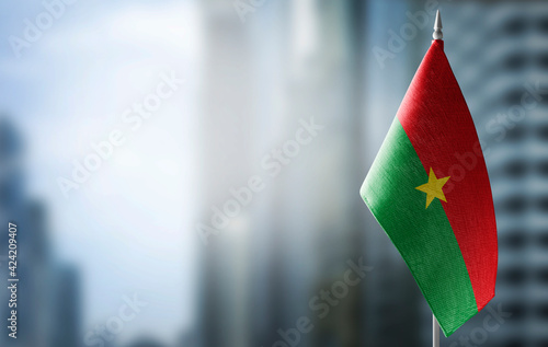 A small flag of Burkina Faso on the background of a blurred background