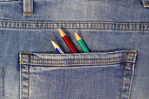 Bright simple pencils in a blue denim pocket, close-up fabric texture