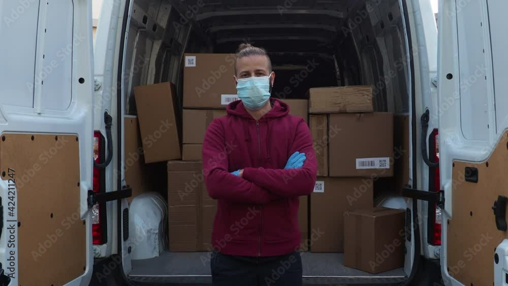 Portrait of a young man shipper with his van during the delivery round in the global pandemic from Covid-19 Coronavirus wearing face mask - Courier with parcels loaded into the open vehicle Portrait of a young man shipper with his van during the delivery round in the global pandemic from Covid-19 Coronavirus wearing face mask - Courier with parcels loaded into the open vehicle