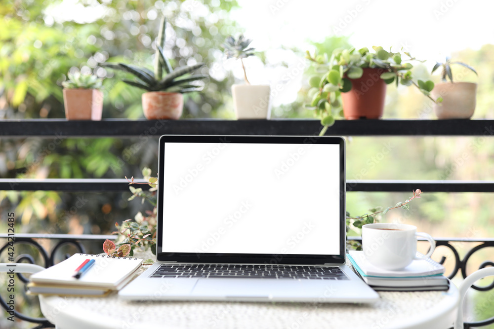 Fototapeta premium Laptop white mock up blank screen and notebooks and coffee cup on white table outdoor
