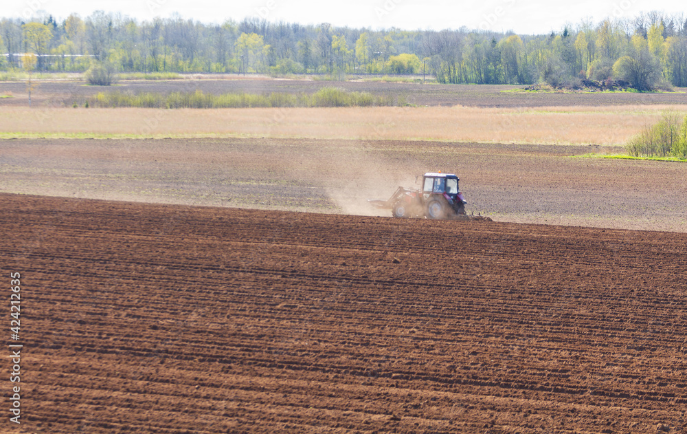 Fototapeta premium tractor plows the field on a sunny spring day