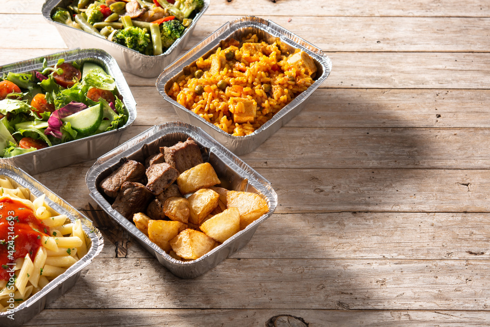 Take away healthy food in foil boxes on wooden table. Copy space Take away healthy food in foil boxes on wooden table. Copy space