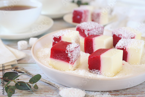 Homemade panna cotta and red fruits cubes in coconut flakes and two cups of tea