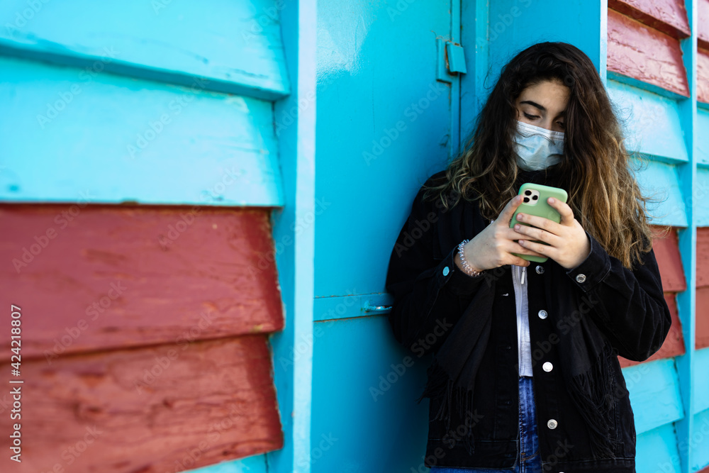 brunette woman looks at mobile phone on blue and maroon wall brunette woman looks at mobile phone on blue and maroon wall