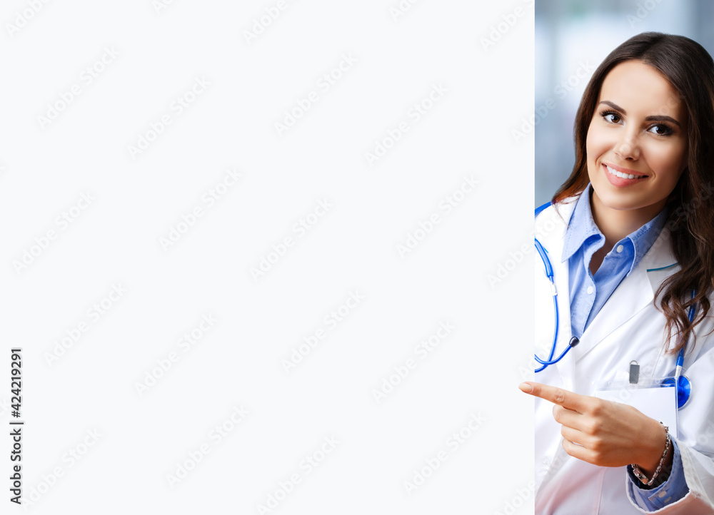 Portrait image of happy smiling female doctor pointing blank signboard with copy space empty area for some text, at office. Young brunette beautiful woman in medical, clinic, healthcare concept Portrait image of happy smiling female doctor pointing blank signboard with copy space empty area for some text, at office. Young brunette beautiful woman in medical, clinic, healthcare concept