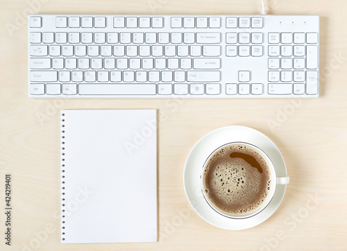 cup of coffee, keyboard and notepad on light wooden background photo