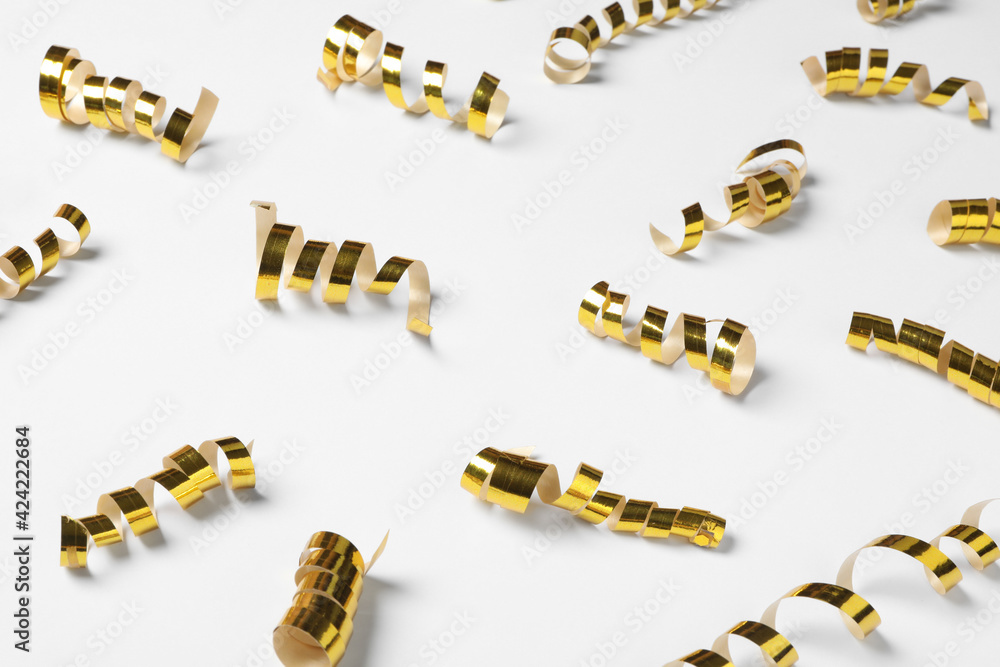 Shiny golden serpentine streamers on white background