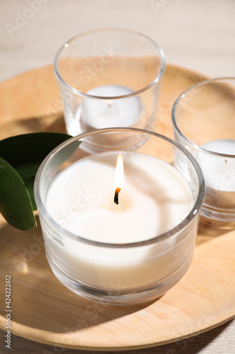 Wooden plate with burning small candles on table, closeup