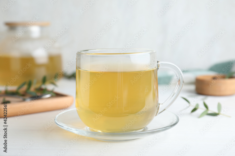 Glass cup of aromatic eucalyptus tea on white wooden table, closeup Glass cup of aromatic eucalyptus tea on white wooden table, closeup