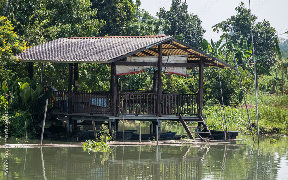 The old wooden pavilion with a small boat below near the small river. The old wooden pavilion with a small boat below near the small river.