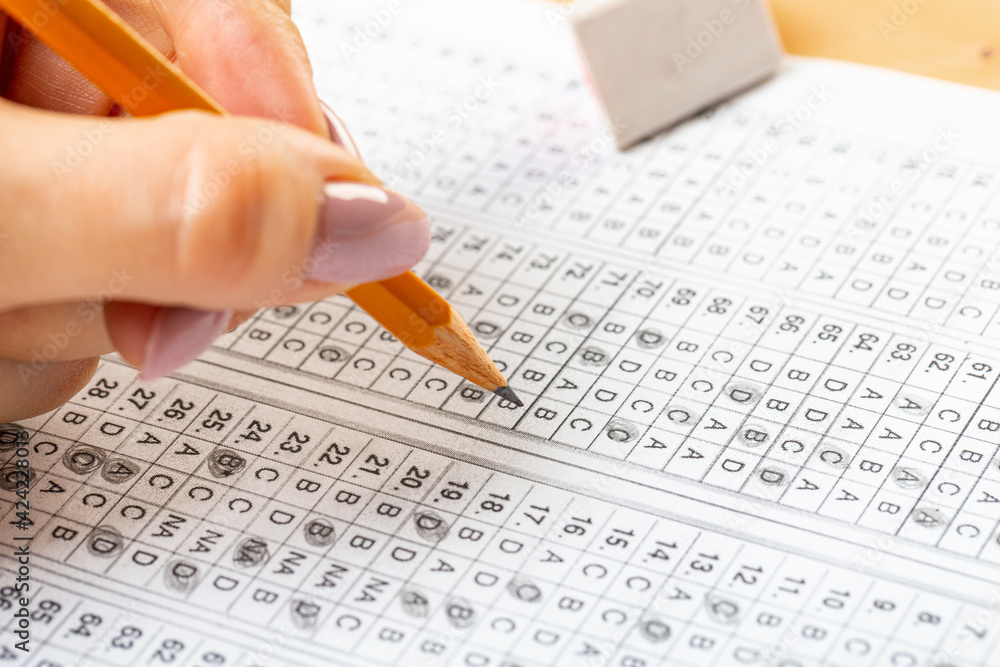 Obraz premium The student fills in the answers to the test in the exercise and examination paper with a pencil. education concept.