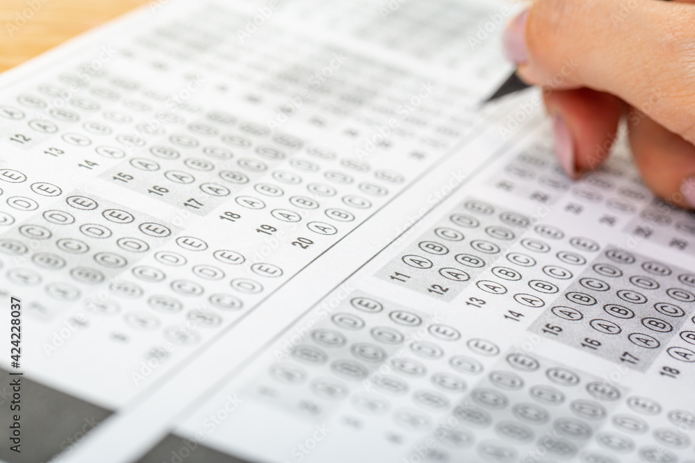 The student fills in the answers to the test in the exercise and examination paper with a pencil. education concept. The student fills in the answers to the test in the exercise and examination paper with a pencil. education concept.