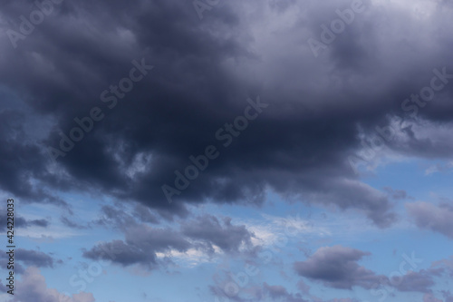 Thunderstorm clouds texture. Storm sky with dark rainy cumulus clouds against blue sky background 