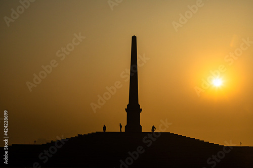 a beautiful silhouette view of sunrise and an ancient pillar in delhi.