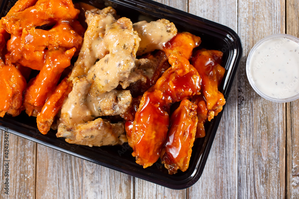 Fotografie A top down view of a to-go container of assorted flavors of chicken wings