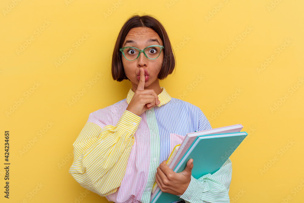 Young mixed race student woman isolated on yellow background keeping a secret or asking for silence. Young mixed race student woman isolated on yellow background keeping a secret or asking for silence.