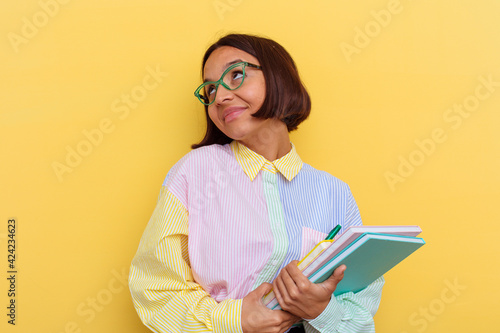 Young mixed race student woman isolated on yellow background dreaming of achieving goals and purposes