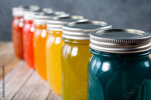 A view of a row of glass mason jars with a rainbow color scheme.