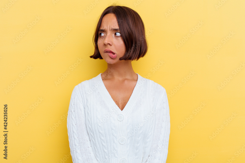 Young mixed race woman isolated on yellow background confused, feels doubtful and unsure. Young mixed race woman isolated on yellow background confused, feels doubtful and unsure.