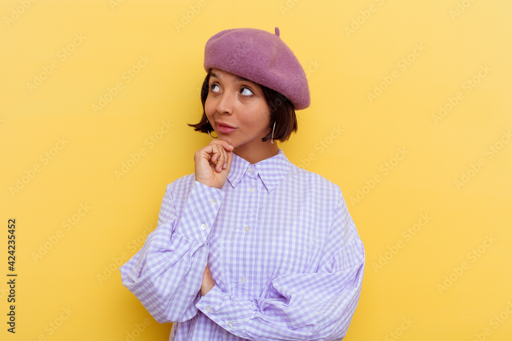 Young mixed race woman wearing a beret isolated on yellow background looking sideways with doubtful and skeptical expression. Young mixed race woman wearing a beret isolated on yellow background looking sideways with doubtful and skeptical expression.