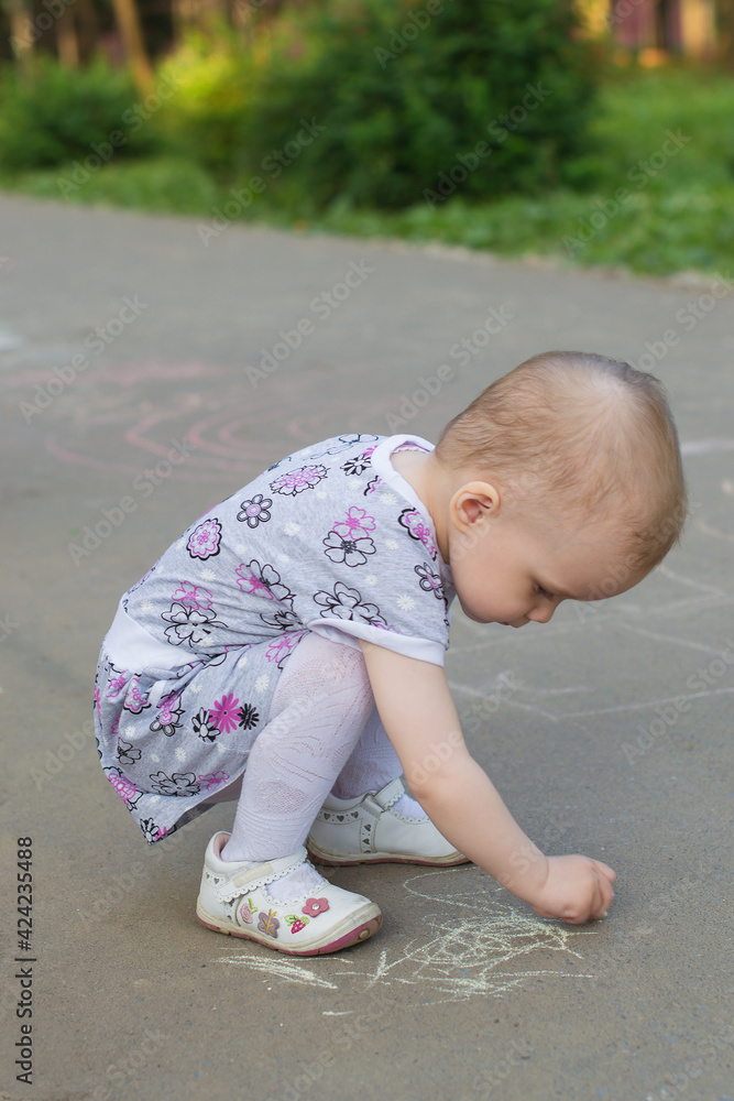 preschool girl paints with chalk on the asphalt preschool girl paints with chalk on the asphalt