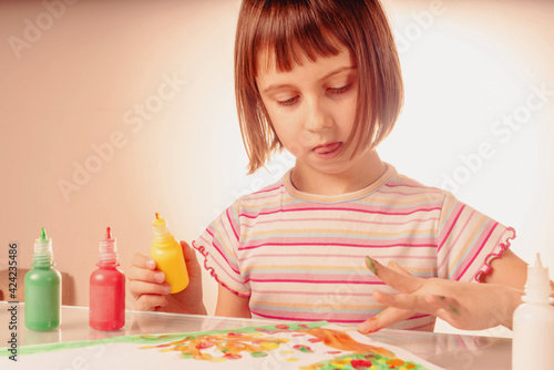 Beautiful young girl painting picture with colorful painted hands. Horizontal image.