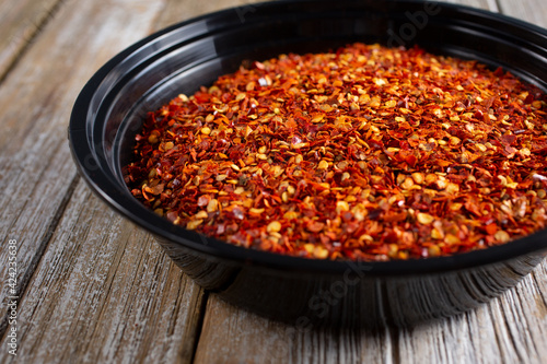 A closeup view of a bowl of crushed red pepper flakes.