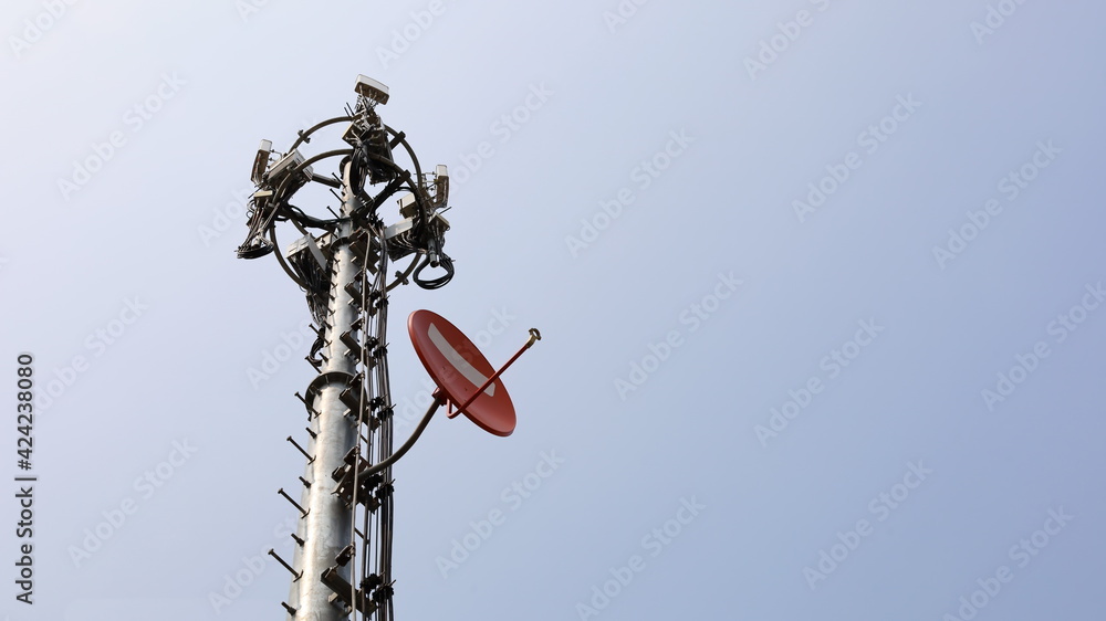 Metal communication towers and equipment. Mobile phone 4G and 5G wireless communication transmitter substation with a satellite dish on a turquoise background with copy space. Selective focus Metal communication towers and equipment. Mobile phone 4G and 5G wireless communication transmitter substation with a satellite dish on a turquoise background with copy space. Selective focus