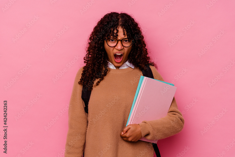 Young student mixed race woman isolated on pink background screaming very angry and aggressive. Young student mixed race woman isolated on pink background screaming very angry and aggressive.