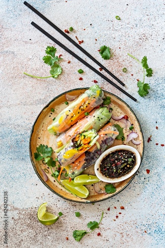 Fresh Asian appetizer Spring rolls (Nem) made from rice paper and raw vegetables and herbs with hot sauce on a light blue background. Vietnamese Food photo