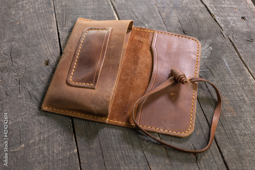 Hand made leather brown tobacco-pouch on wood background. DIY.