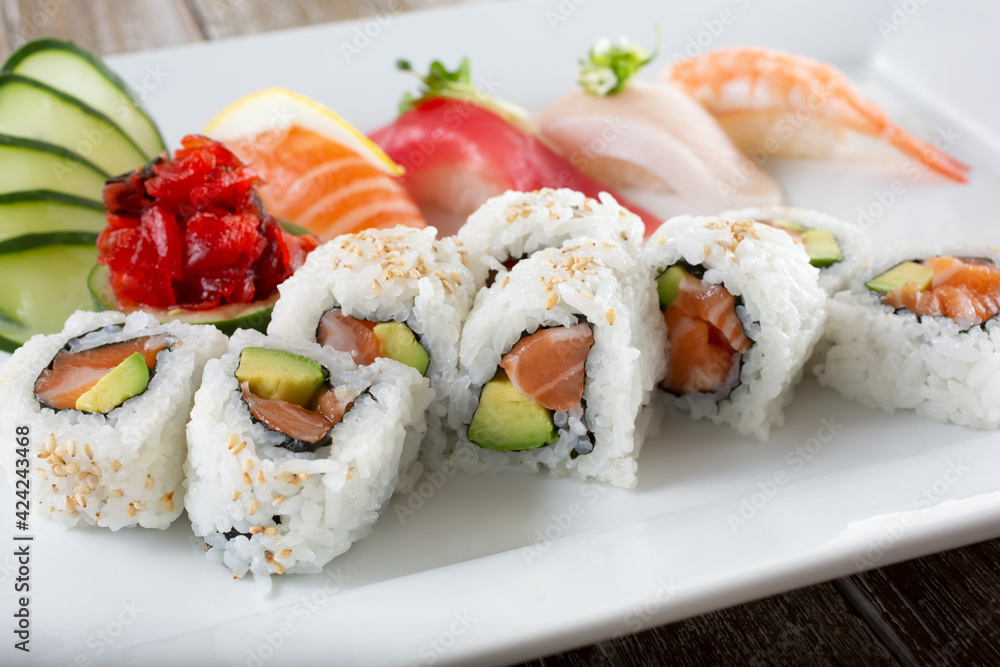 A view of a plate with salmon avocado roll slices and a variety of nigiri. A view of a plate with salmon avocado roll slices and a variety of nigiri.