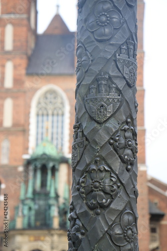 textured pillar in the center of krakow with historical signs wrought flowers and wrought iron gates, towers symbols of the Polish nobility photo