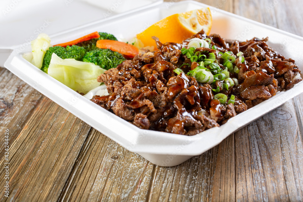 A view of a to-go container of teriyaki beef combination plate. A view of a to-go container of teriyaki beef combination plate.
