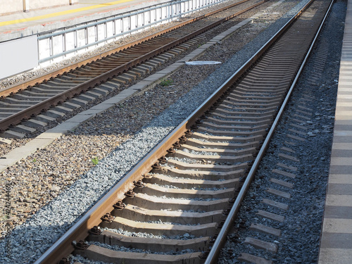 Two parallel railways illuminated by the sun's rays are narrowing in perspective