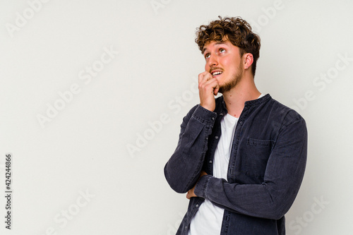 Young caucasian man isolated on white background relaxed thinking about something looking at a copy space.