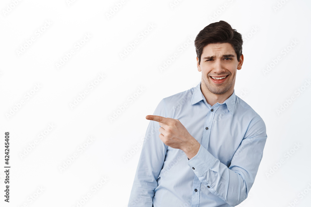 Cool and handsome young man in office clothes, pointing aside at promo banner and smiling sassy, showing logo promo text, recommending something awesome, white background Cool and handsome young man in office clothes, pointing aside at promo banner and smiling sassy, showing logo promo text, recommending something awesome, white background